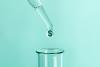 Liquid with dollar sign dropping into test tube, research funding