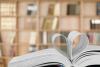 A book with heart-shaped pages in front of a stacked bookcase