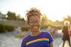 A young woman smiling to camera ourside wearing a t-shirt with a rainbow on it
