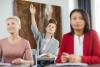 A student raises a hand at the back of class