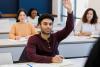 Young male student raising hand in class