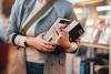 A woman holds a pile of books 