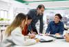 A teacher advises students on their work